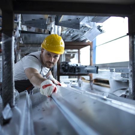 Factory worker working in warehouse handling metal material for production.